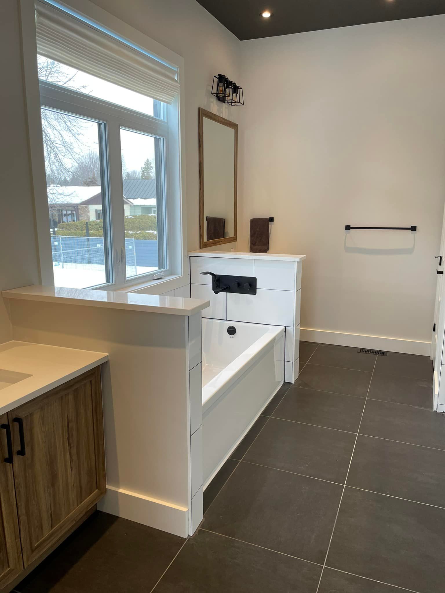 Une salle de bain avec baignoire, lavabo, miroir et fenêtre.