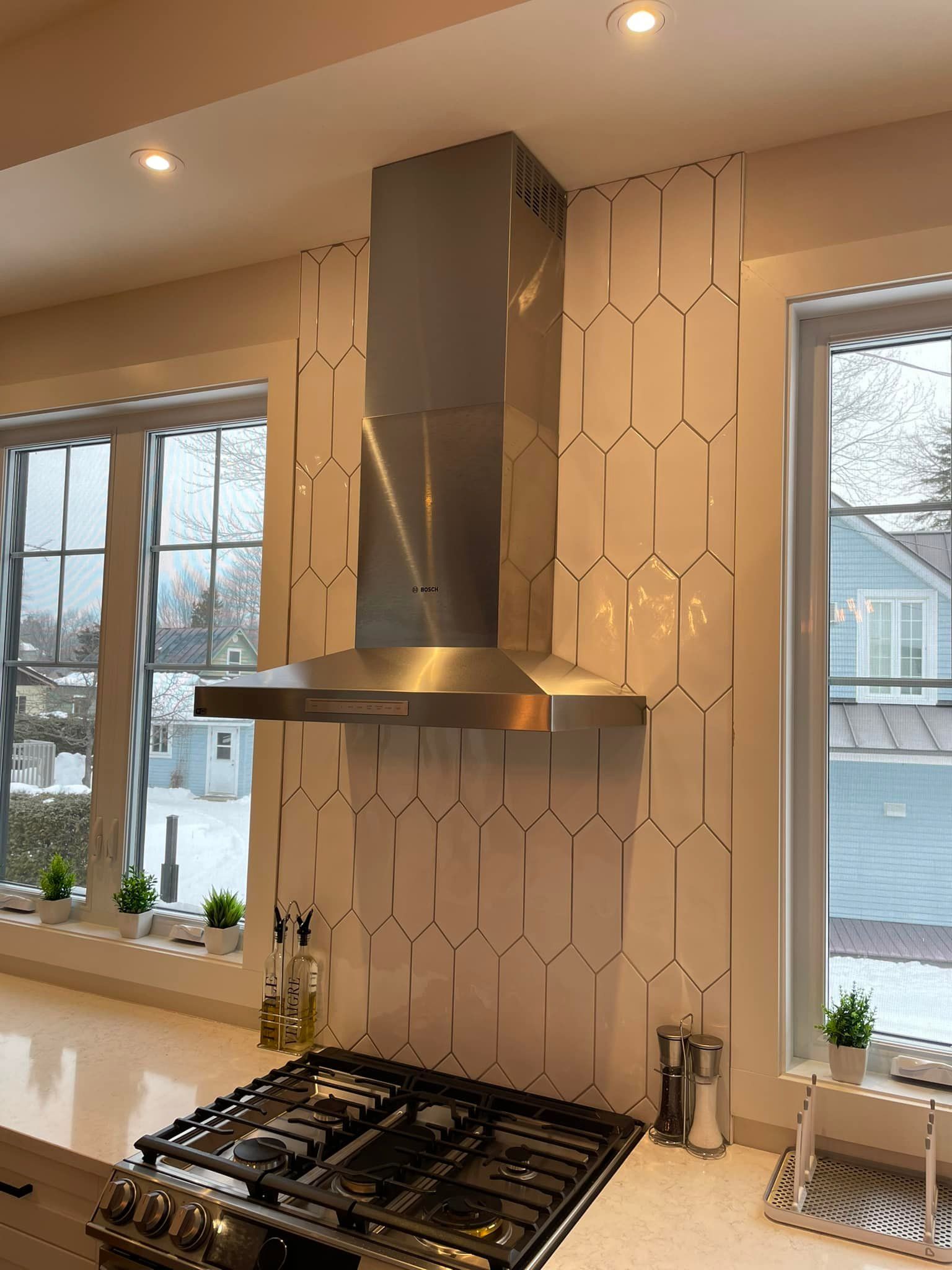 Une cuisine avec une cuisinière et une hotte au-dessus.