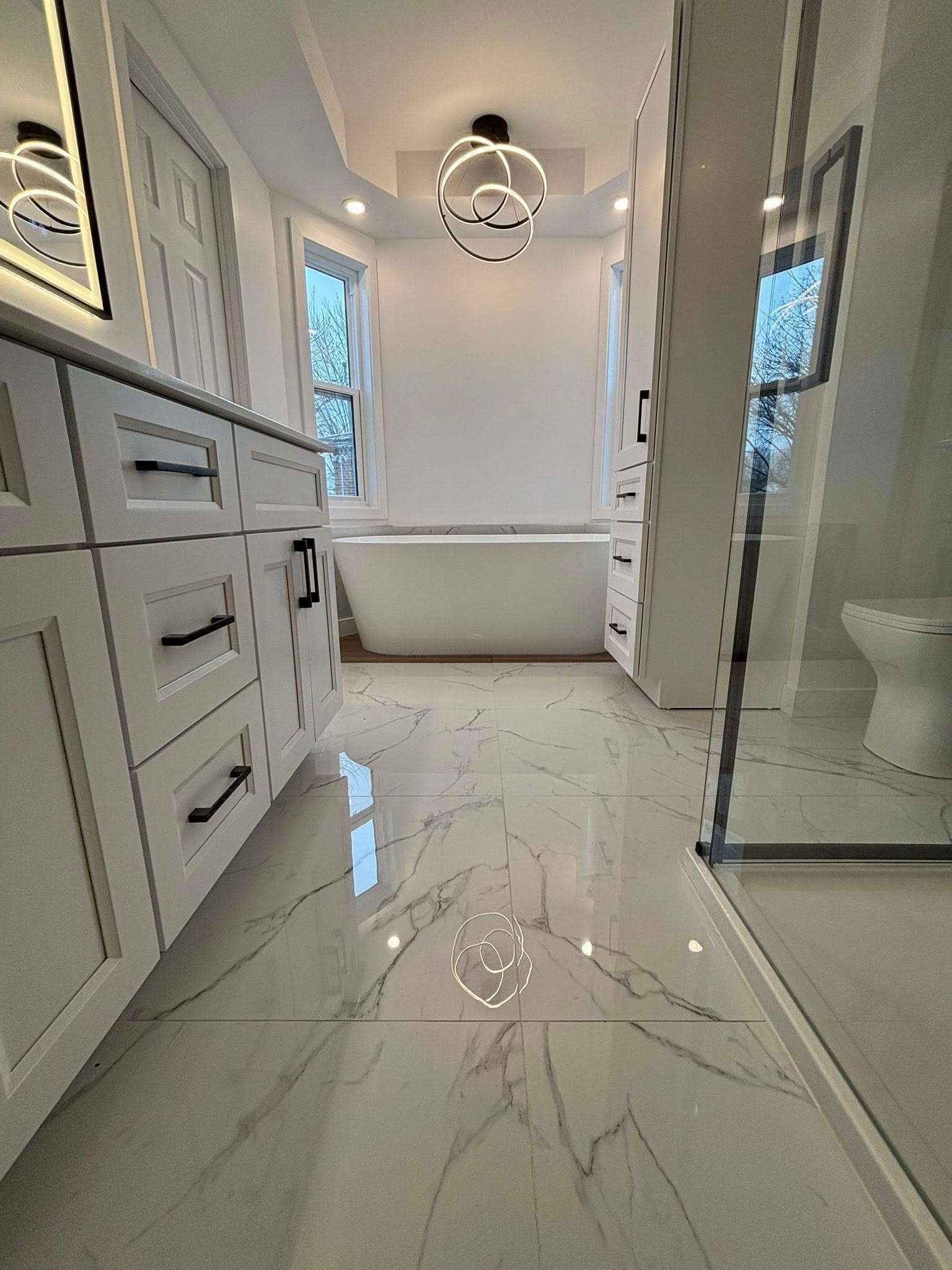 Salle de bains blanche avec sol en marbre, baignoire, meuble-lavabo et douche.