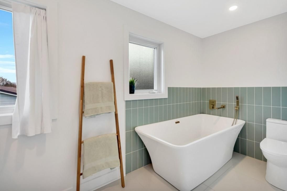 Une salle de bain avec baignoire, toilettes et fenêtre.