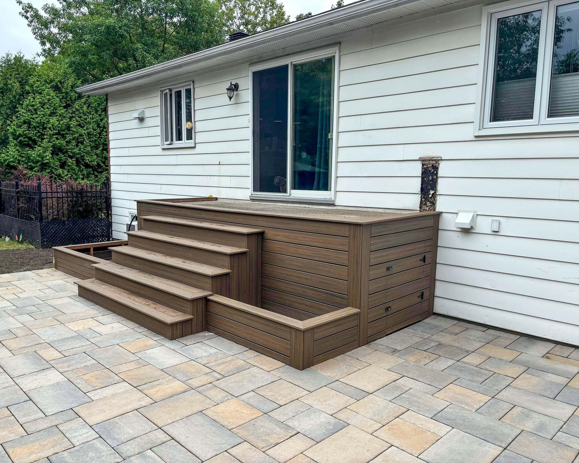 Une maison blanche avec une terrasse en bois et des escaliers devant.