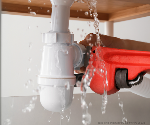 A person is fixing a leaking sink pipe with a wrench.