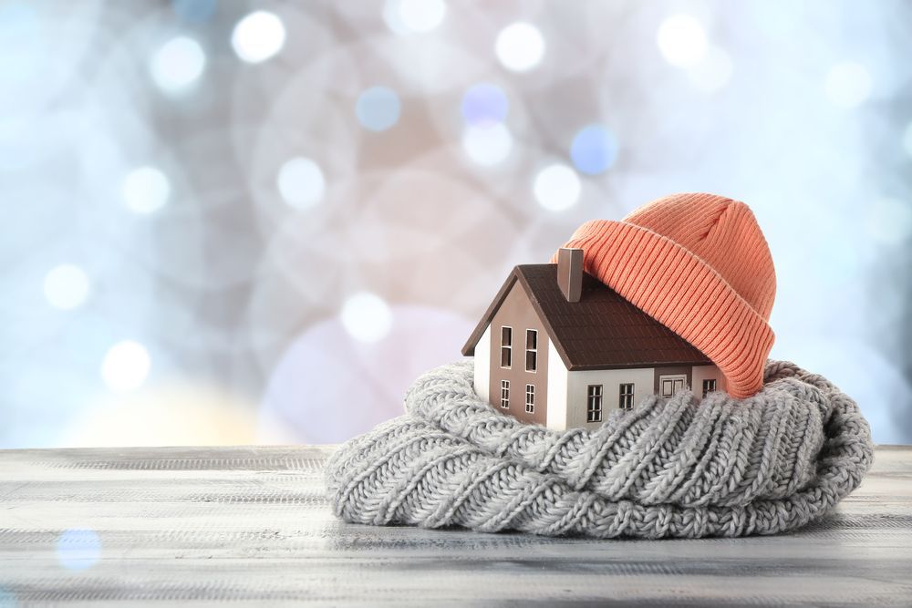 A small house is wrapped in a knitted scarf and hat.