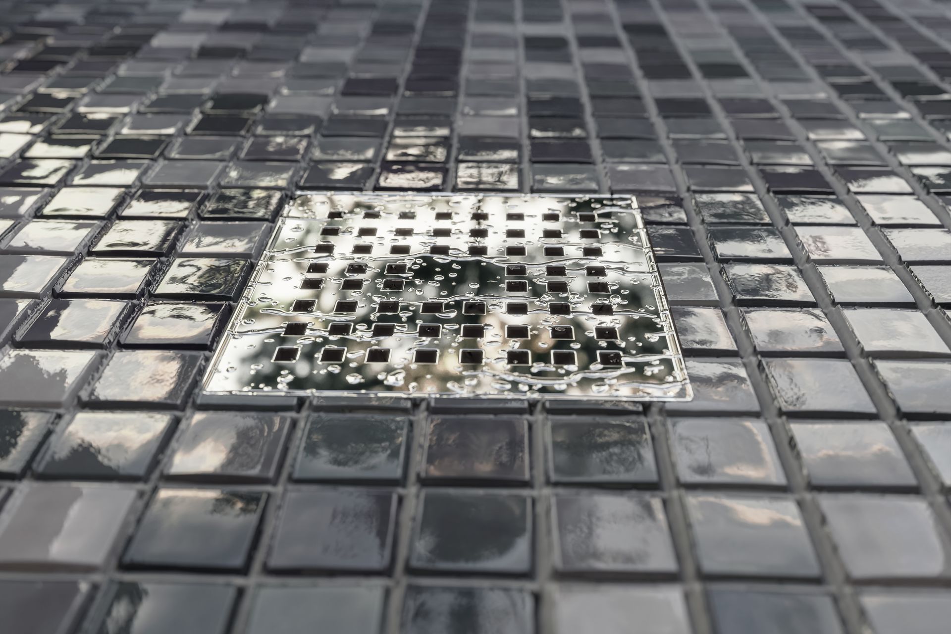 A close up of a drain on a tiled floor.