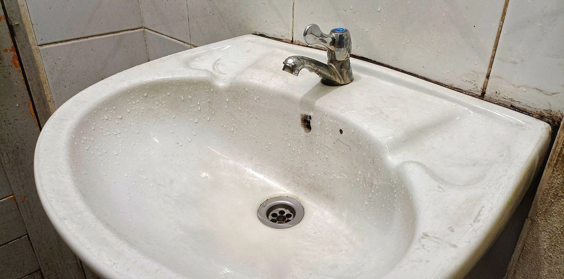 A white bathroom sink with a faucet and drain