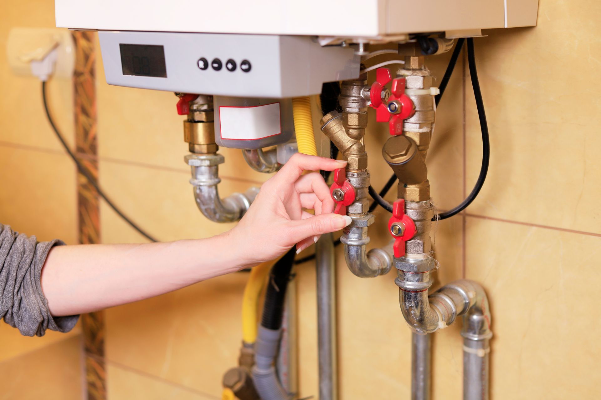 A person is adjusting a valve on a furnace.