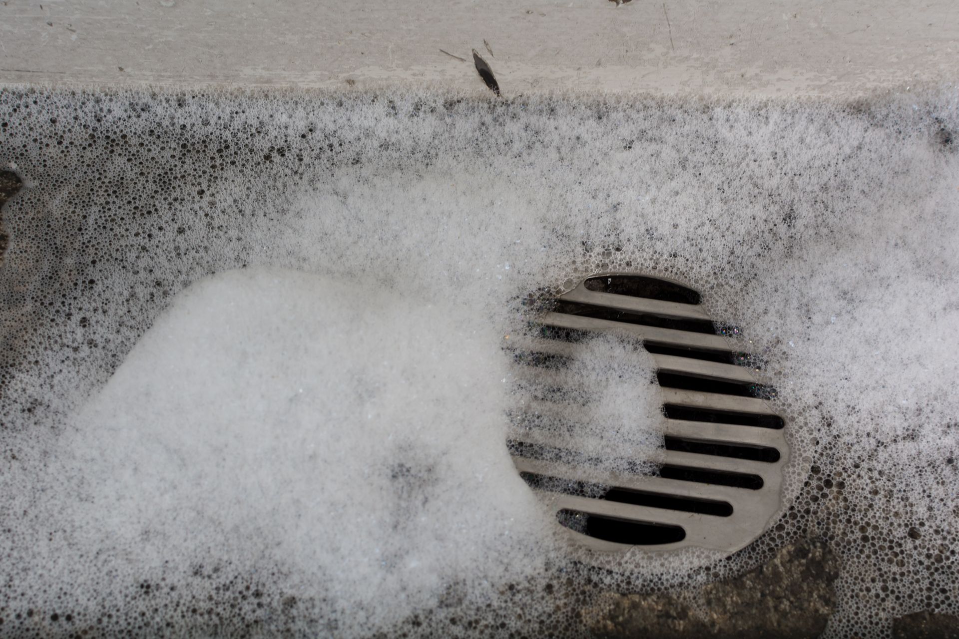 A close up of a drain with foam coming out of it.