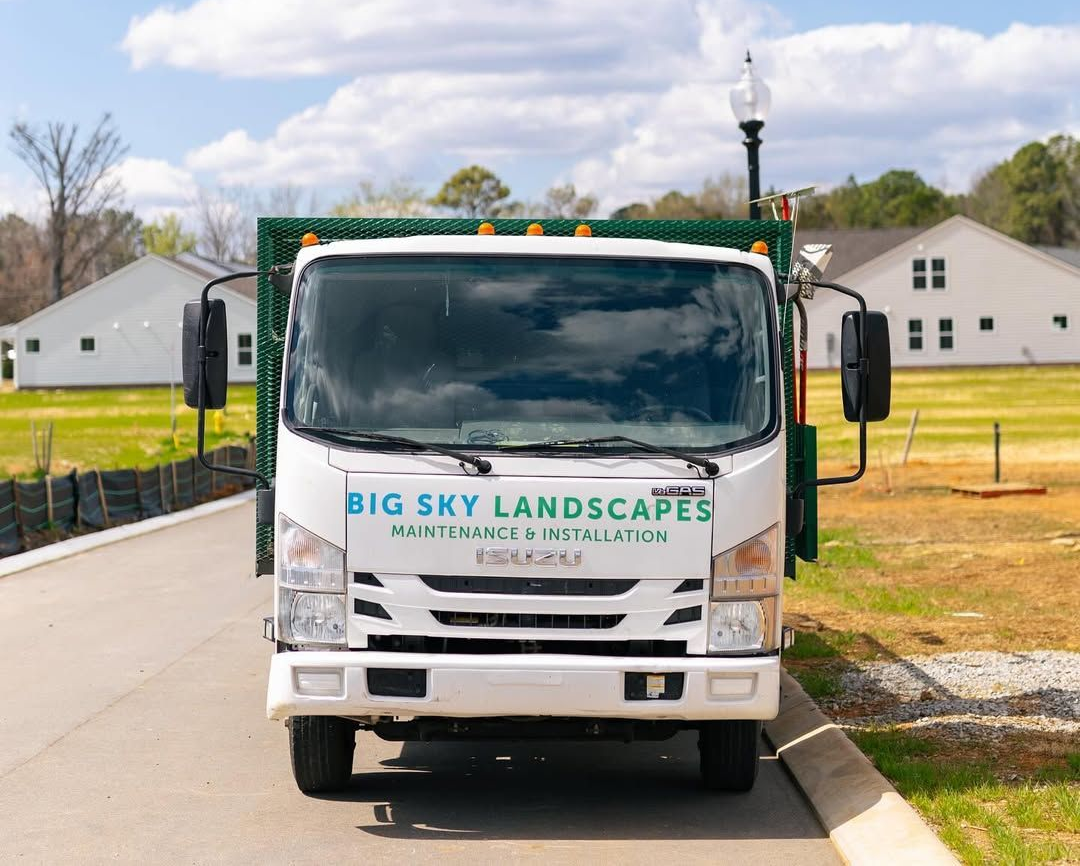 White Big Sky Landscapes truck parked on a road beside lawns and white houses