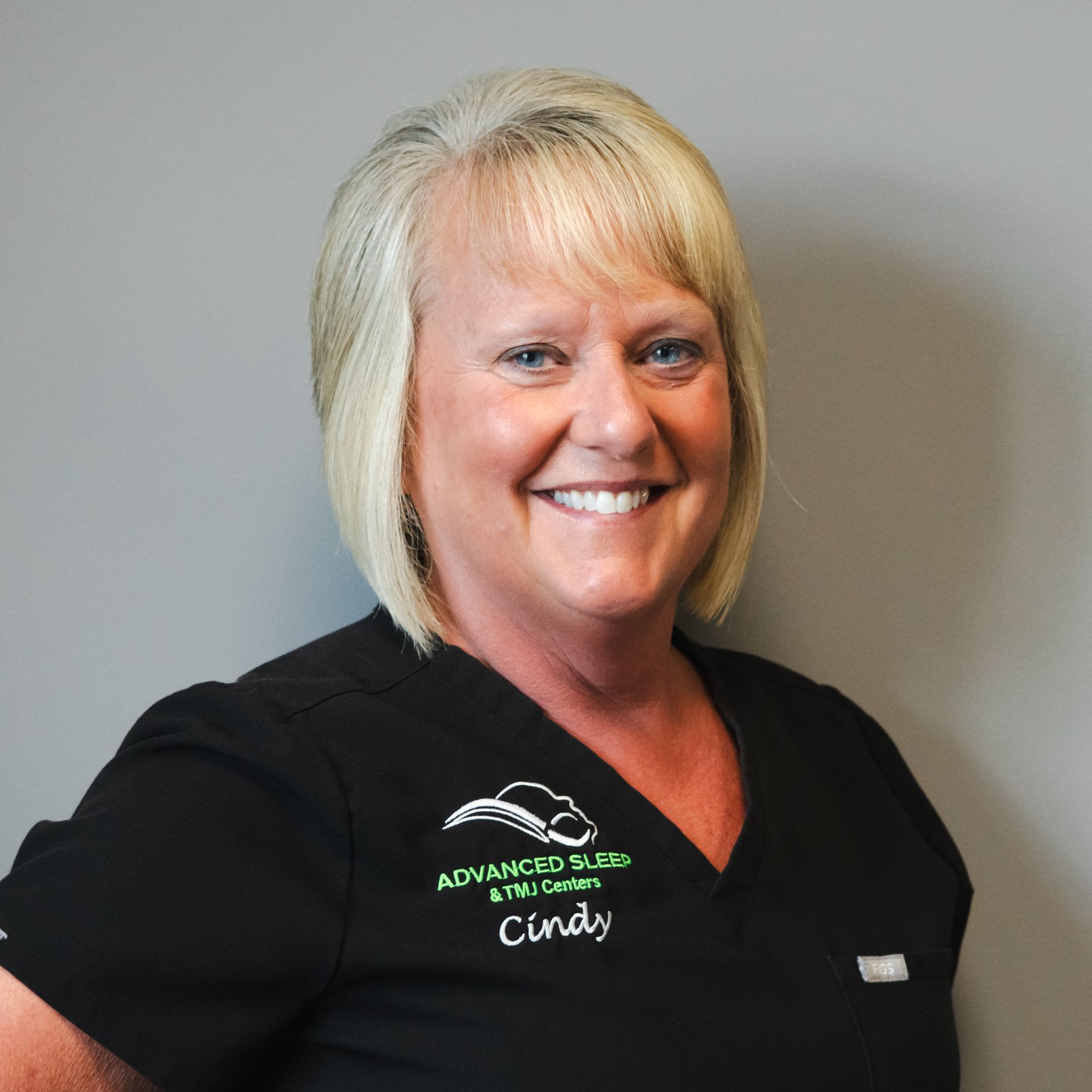 A woman wearing a black scrub top with the name cindy on it