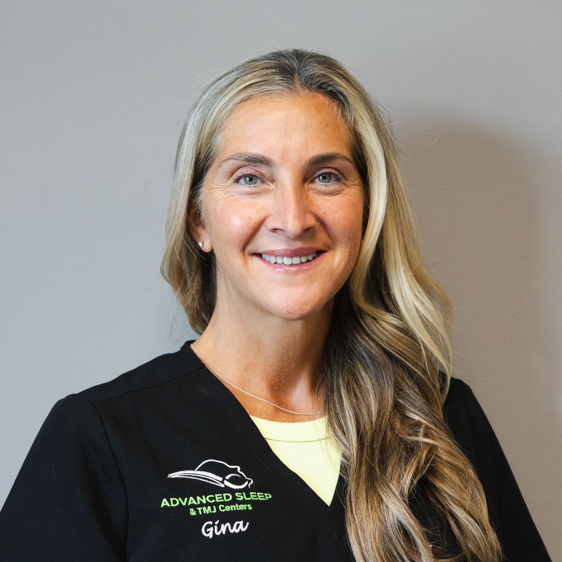 A woman wearing a black scrub top with the name gino on it