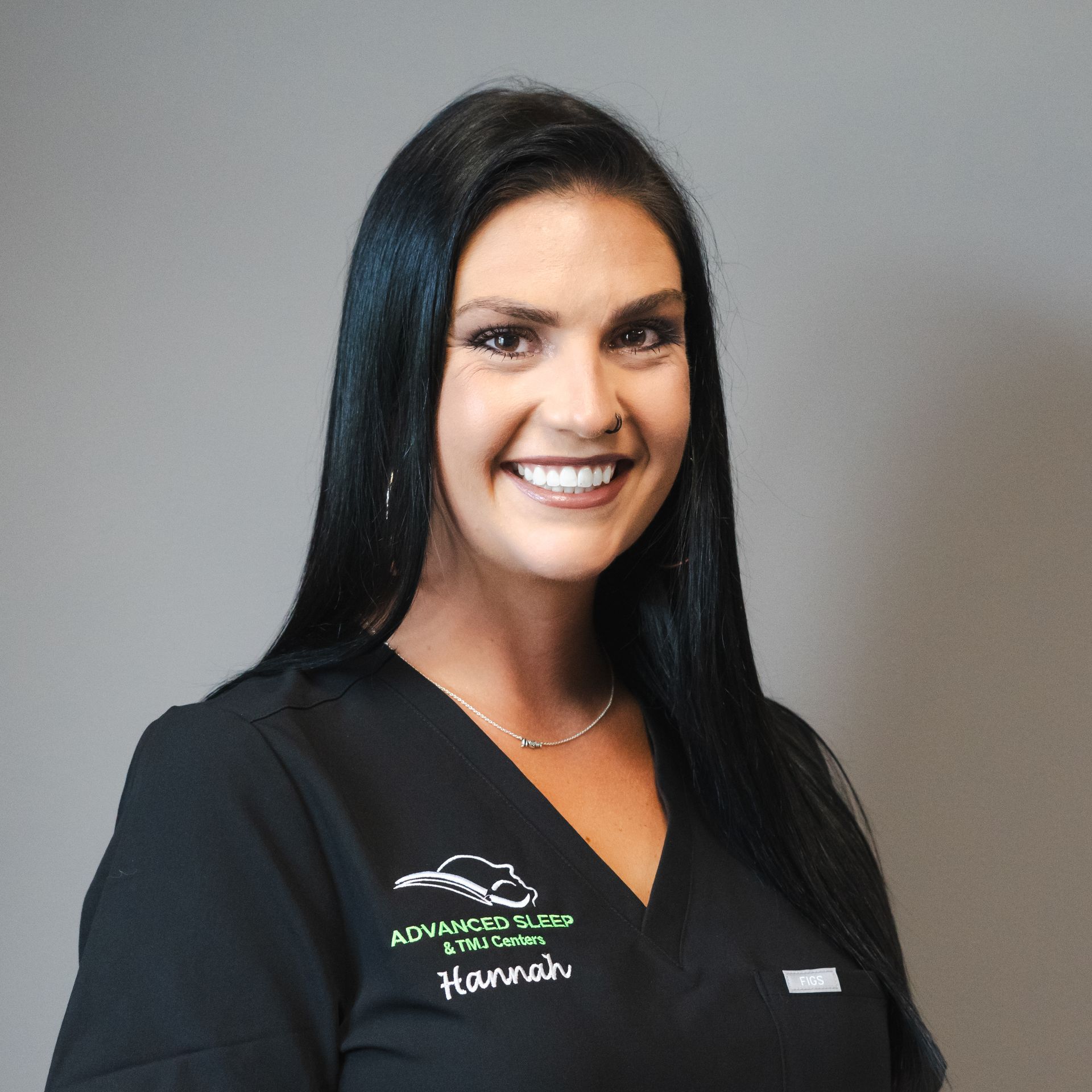 A woman in a black scrub top is smiling for the camera.