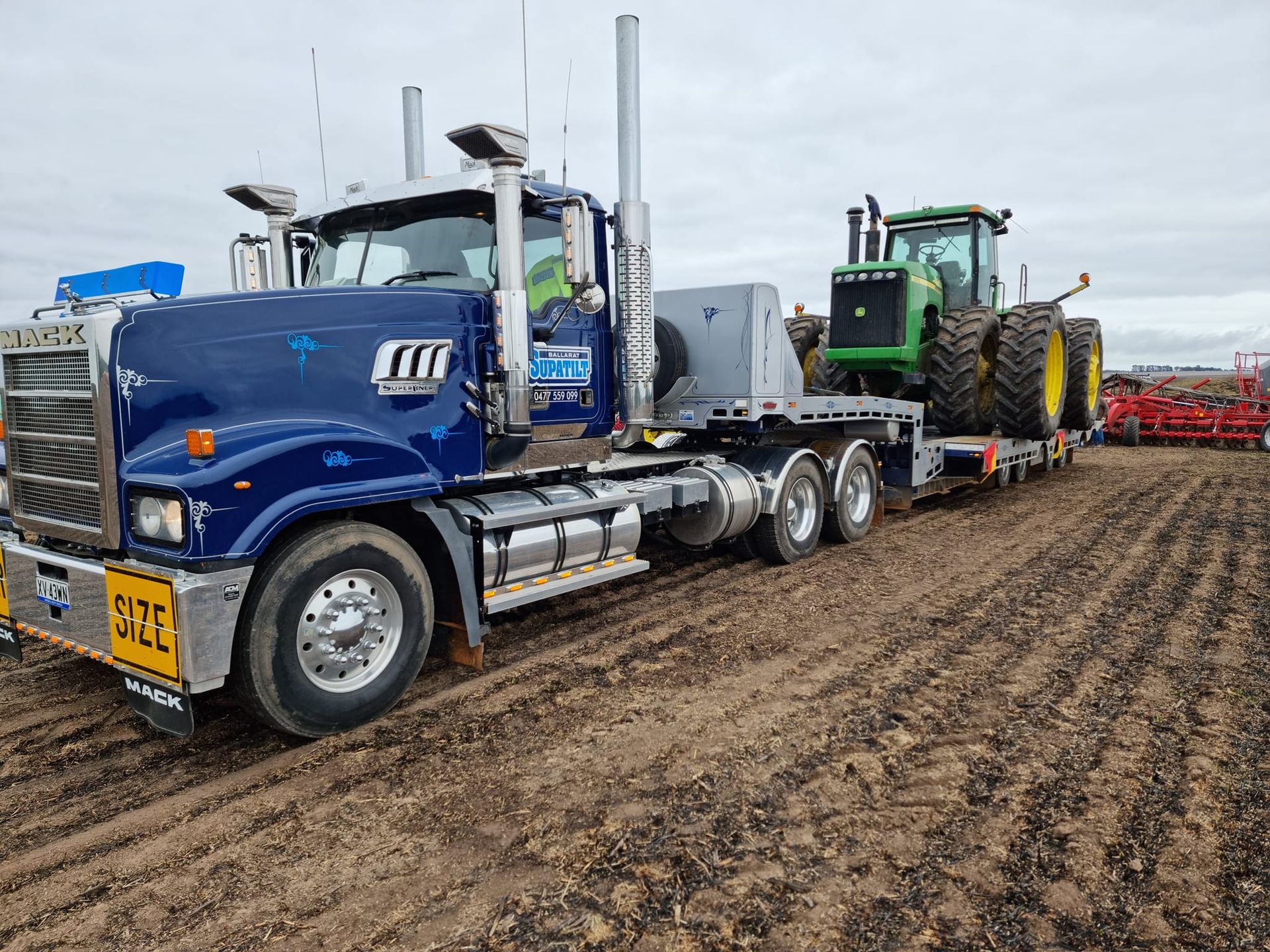 A blue semi truck is carrying a green john deere tractor on a trailer — Ballarat Supatilt in Delacombe, VIC