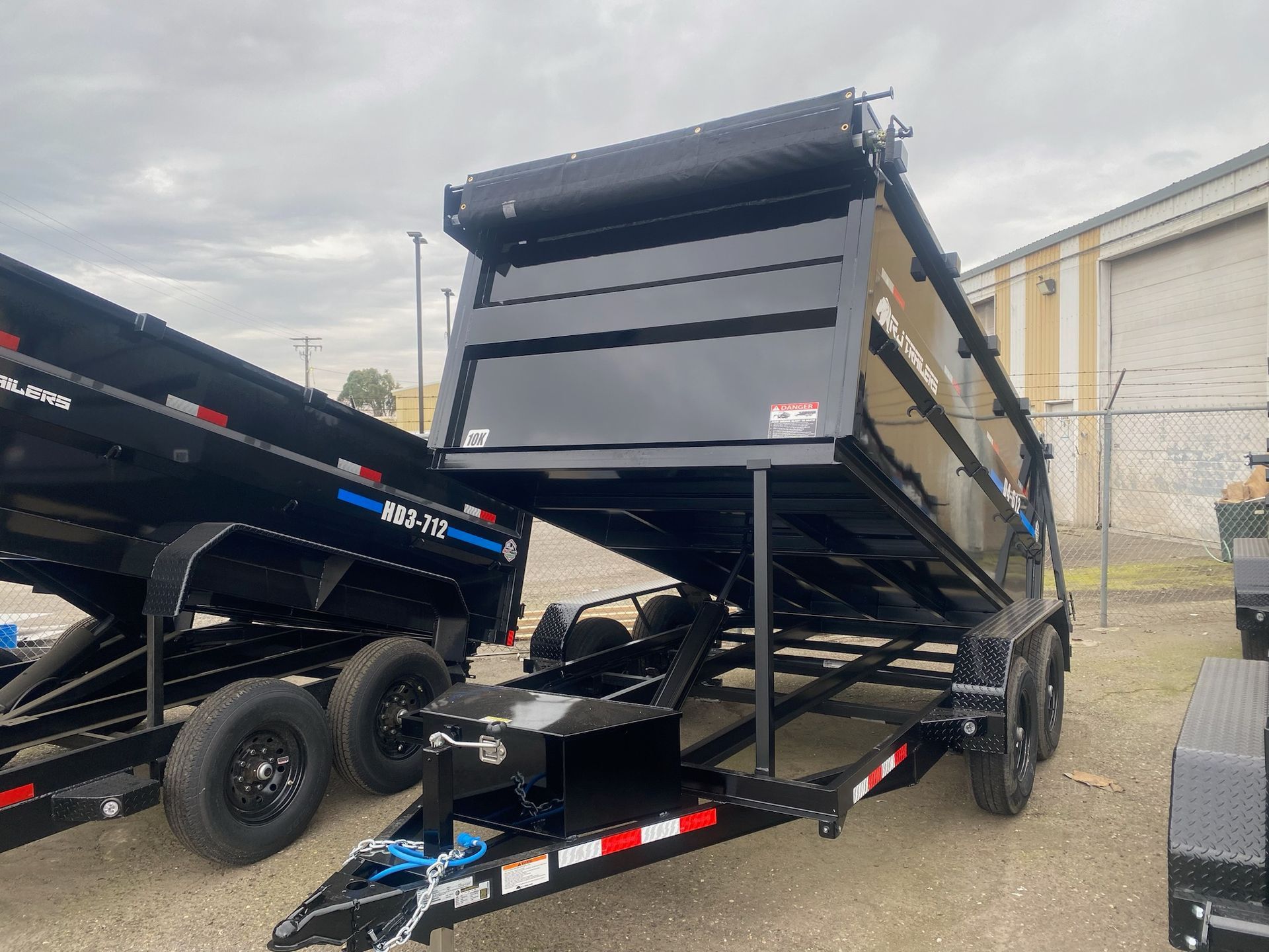 A dump trailer is parked in a parking lot next to a building.