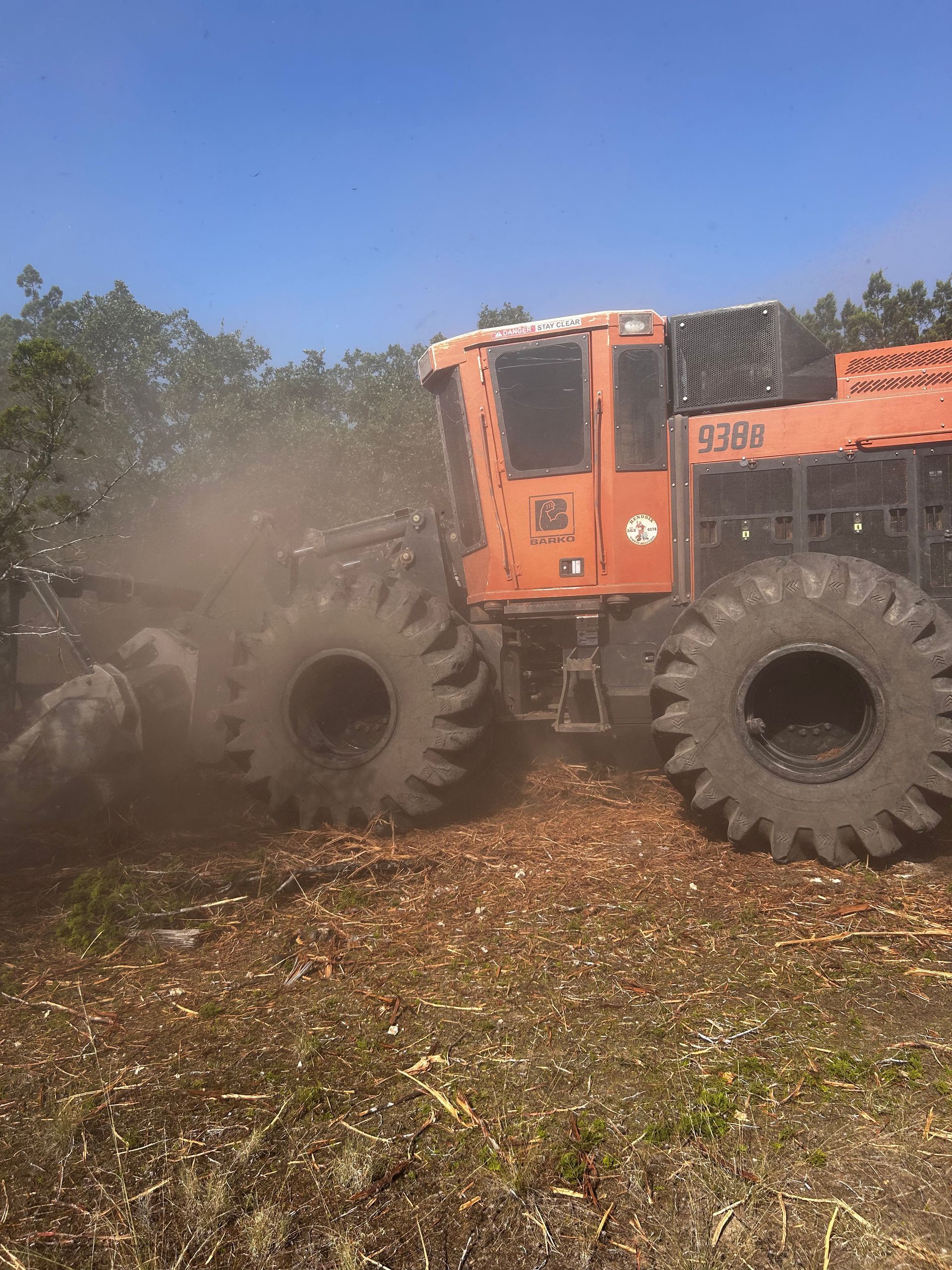 A large orange tractor is driving through a field.