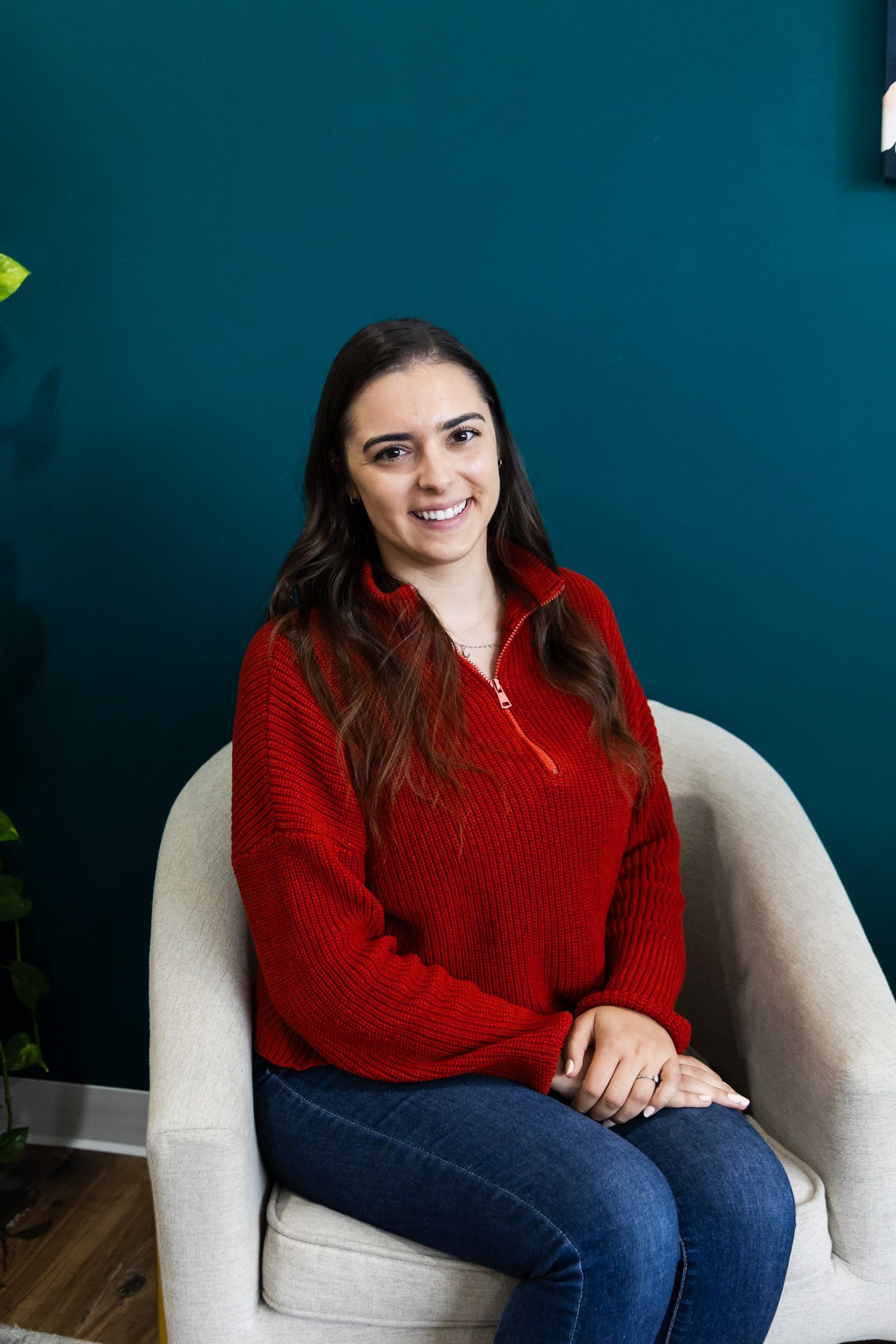 A woman wearing glasses and a colorful jacket is sitting in a yellow chair.