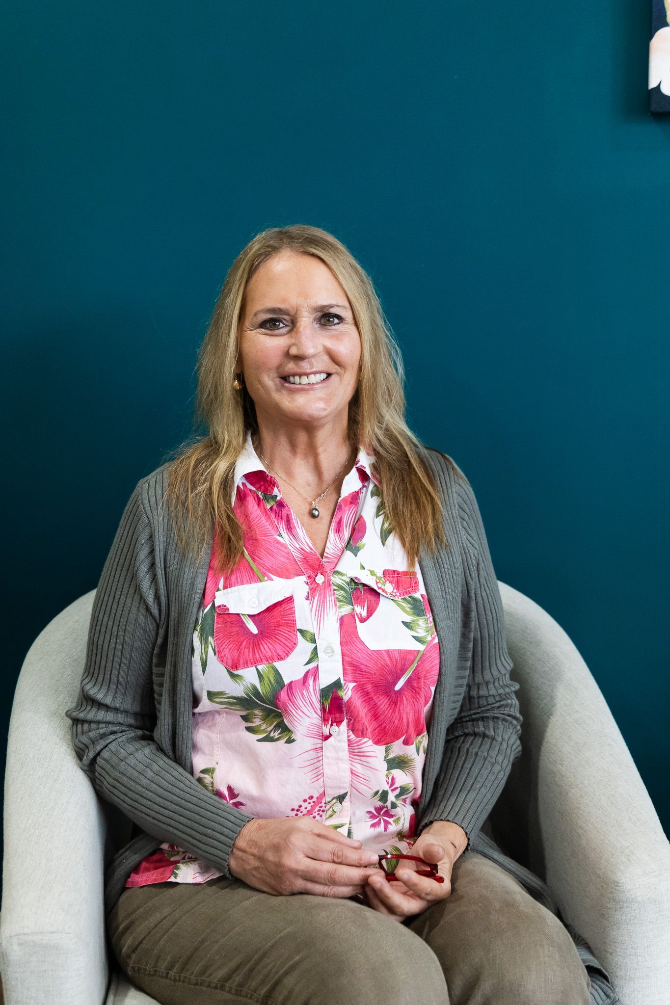 A man in a suit and glasses is sitting in a chair in front of a window.