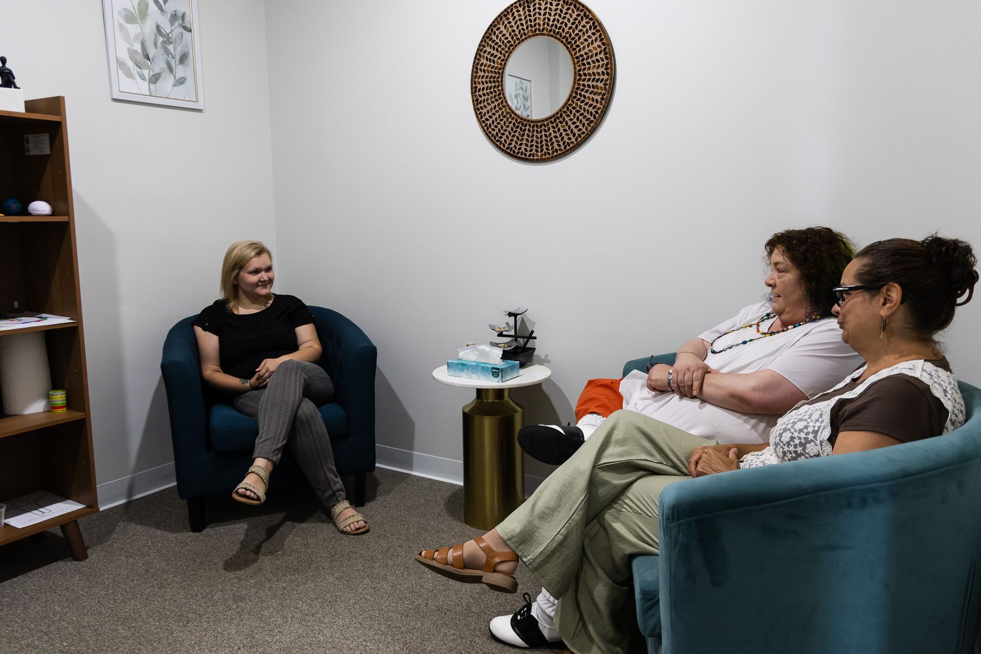 A woman is sitting on a couch talking to a man.