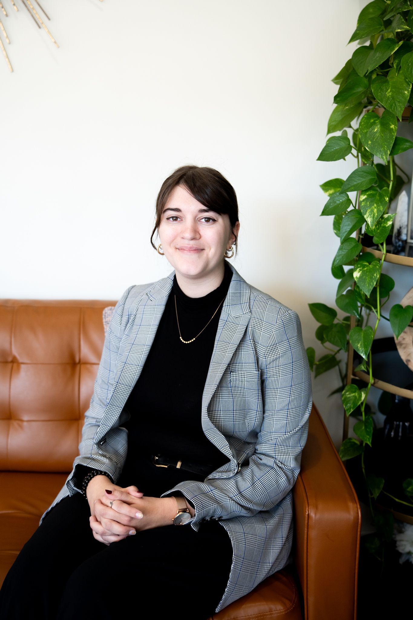 A woman is sitting on a couch with pillows and smiling for the camera.