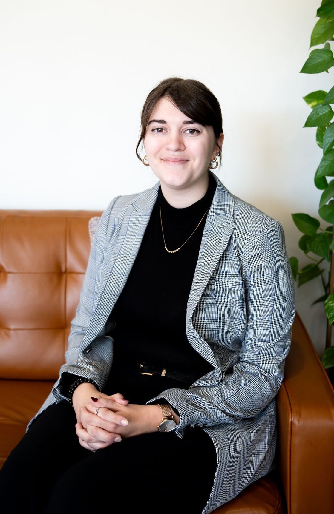 A woman is sitting on a couch with pillows and smiling for the camera.