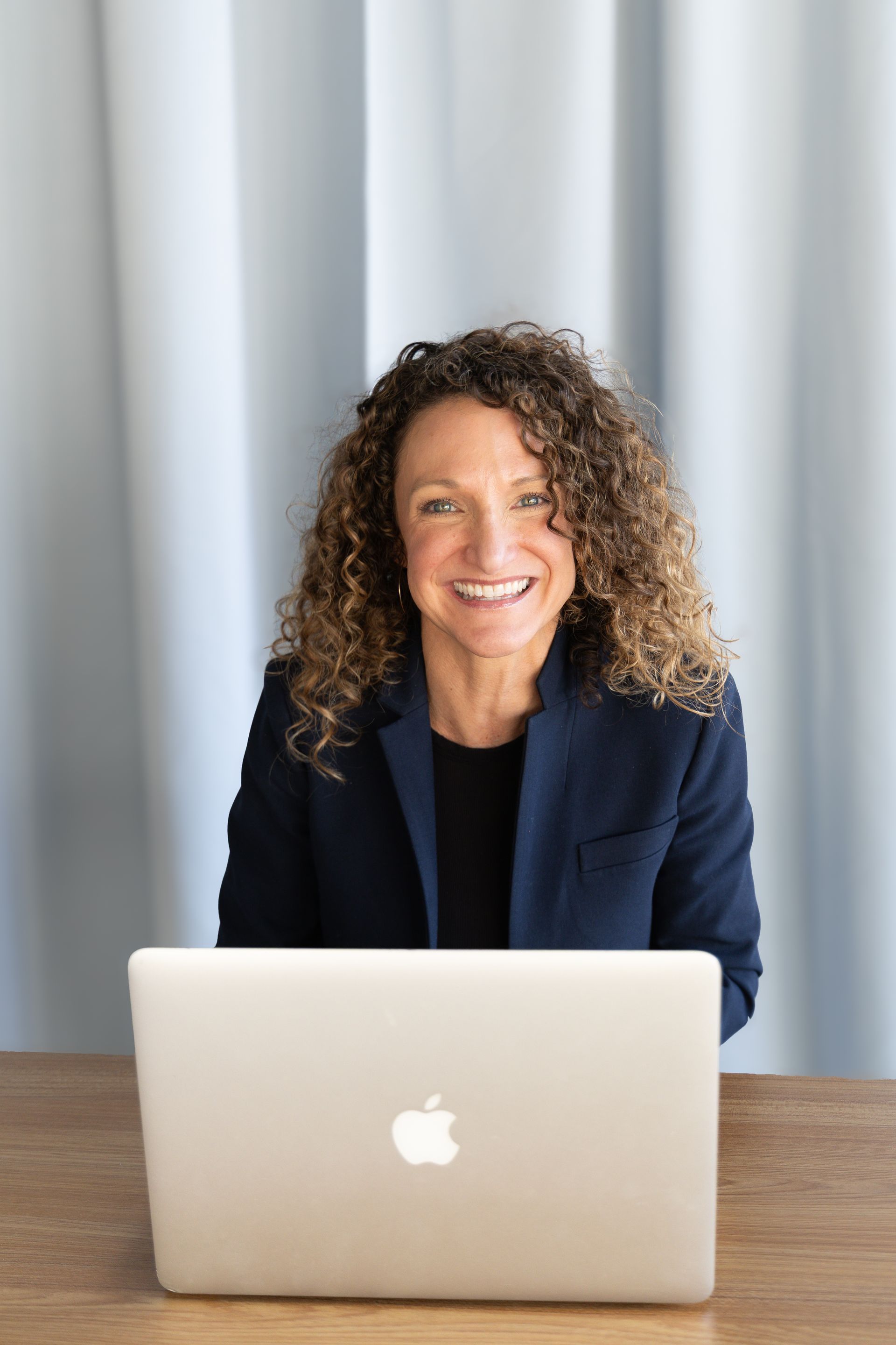 A woman is sitting in a chair with a laptop.