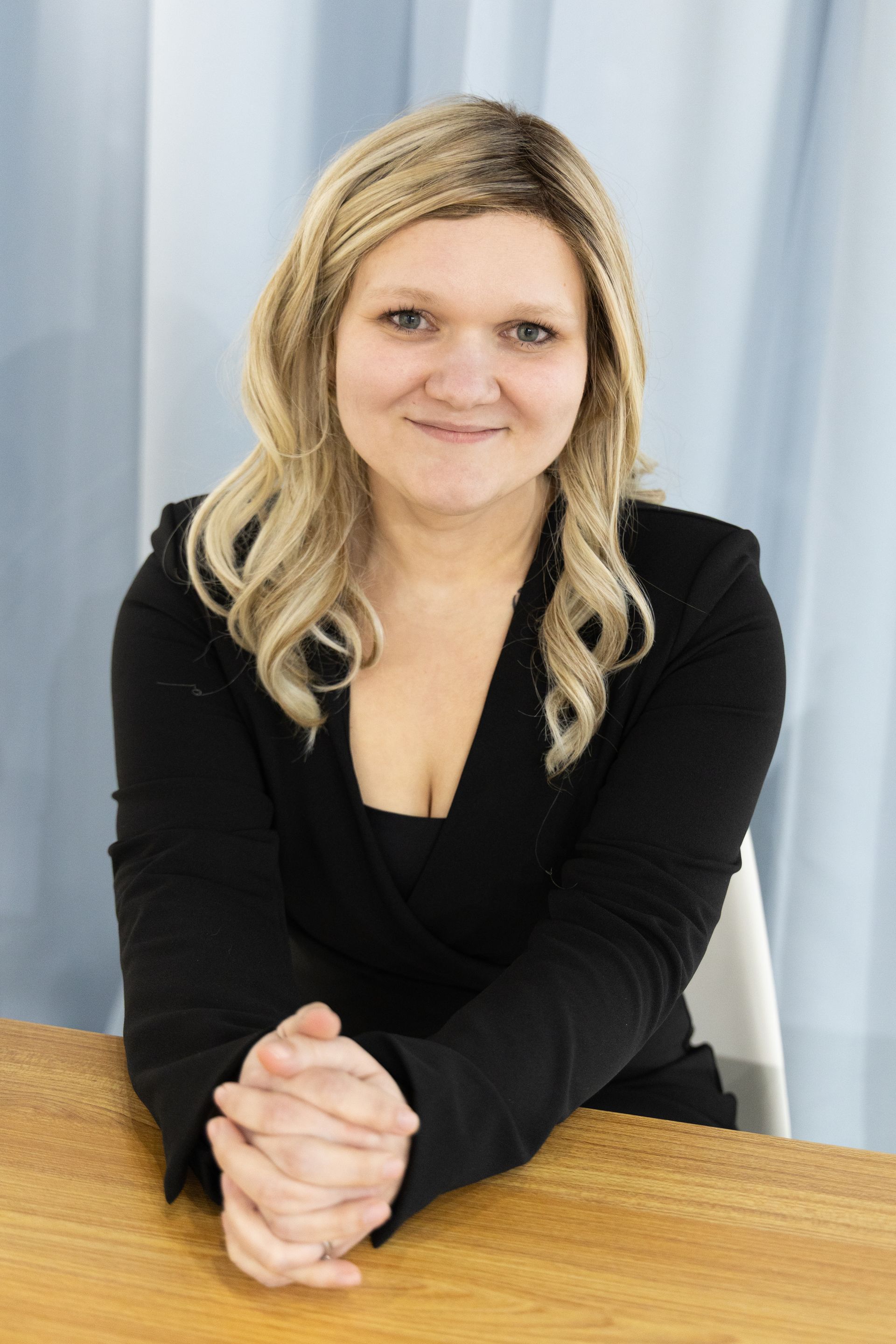 A woman in a green sweater is sitting at a desk.