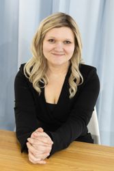 A woman in a green sweater is sitting at a desk.