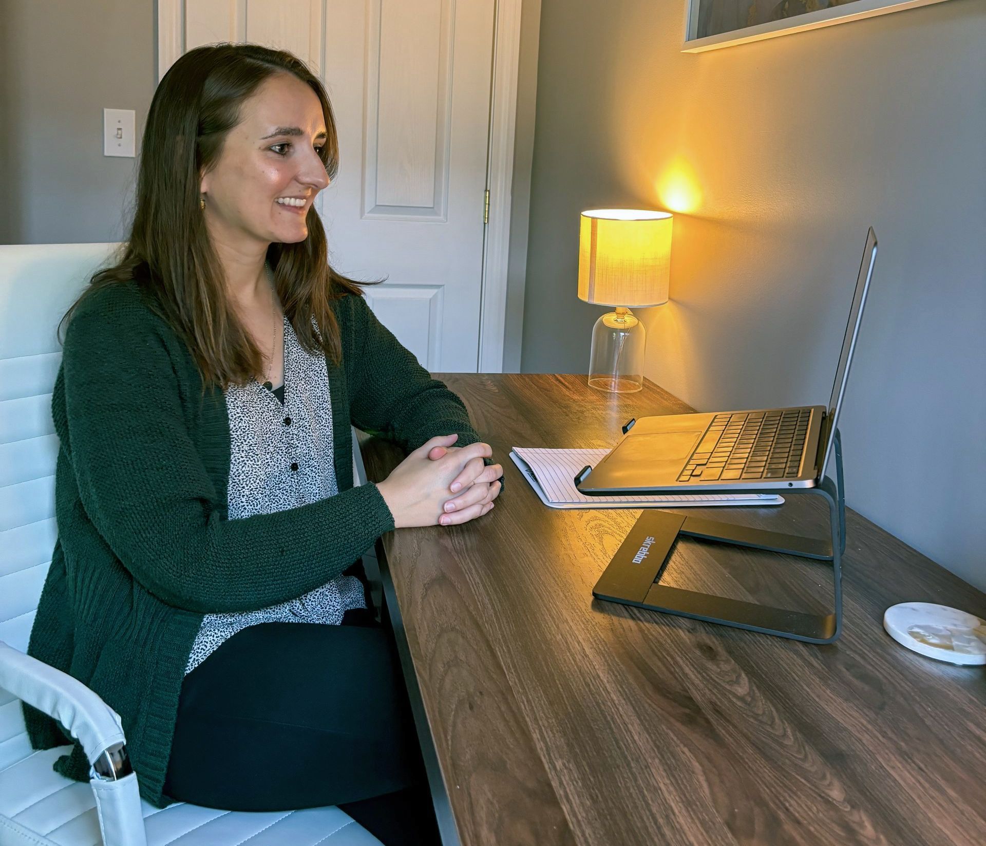 A woman is sitting at a desk using a laptop computer.