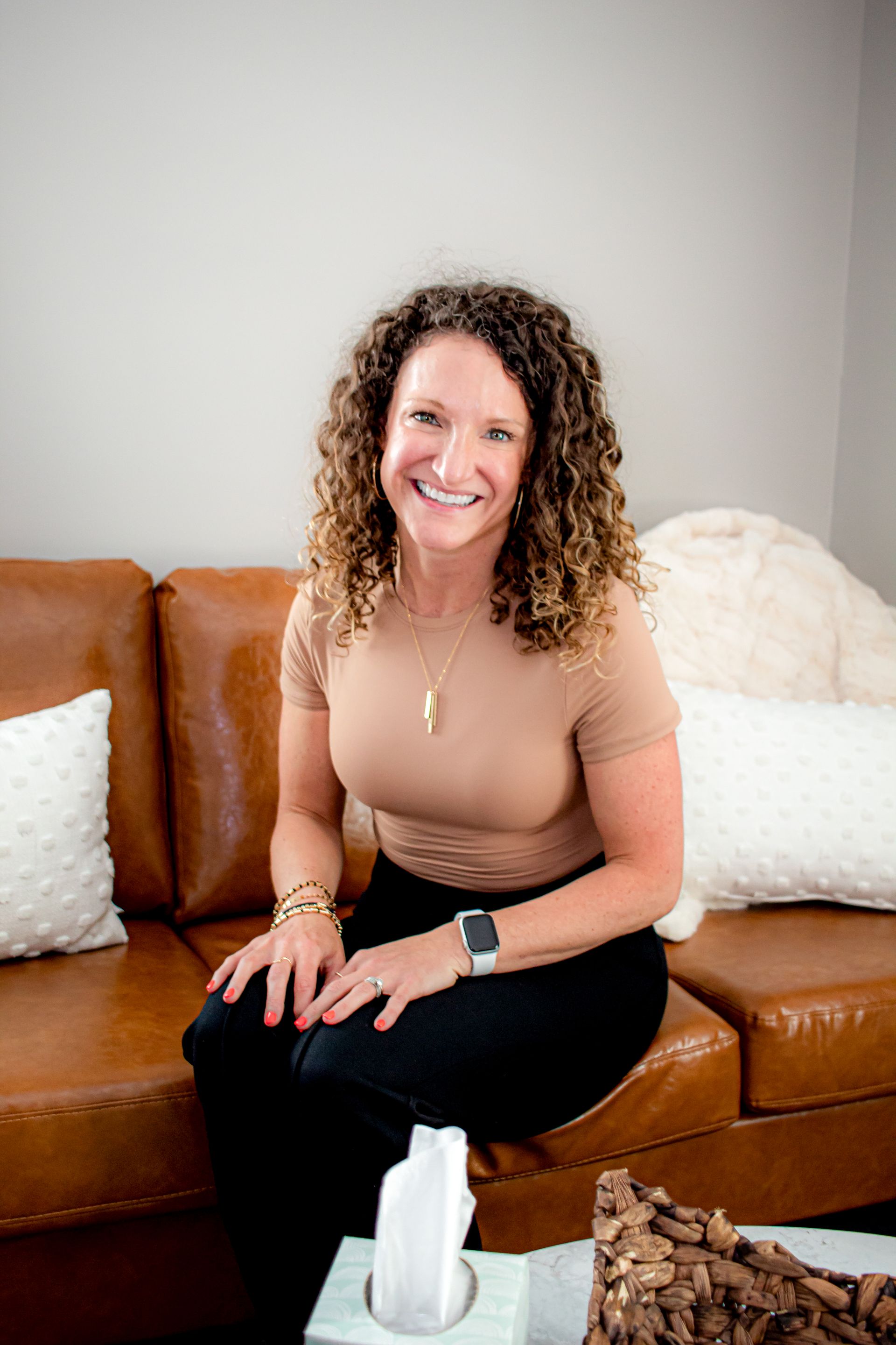 A woman wearing glasses and a blue scarf is sitting in a chair.