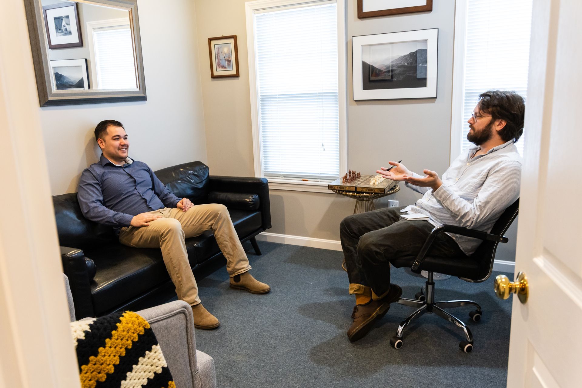A man and a boy are sitting on a couch and talking to each other.