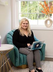 A woman is sitting in a chair with a laptop.