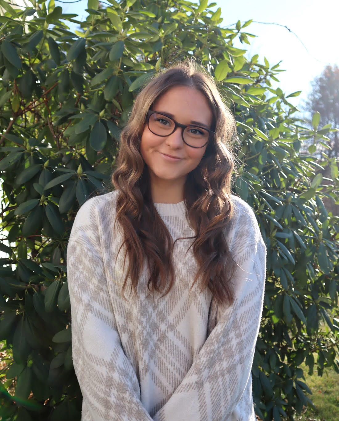 A woman is standing in front of a tree.