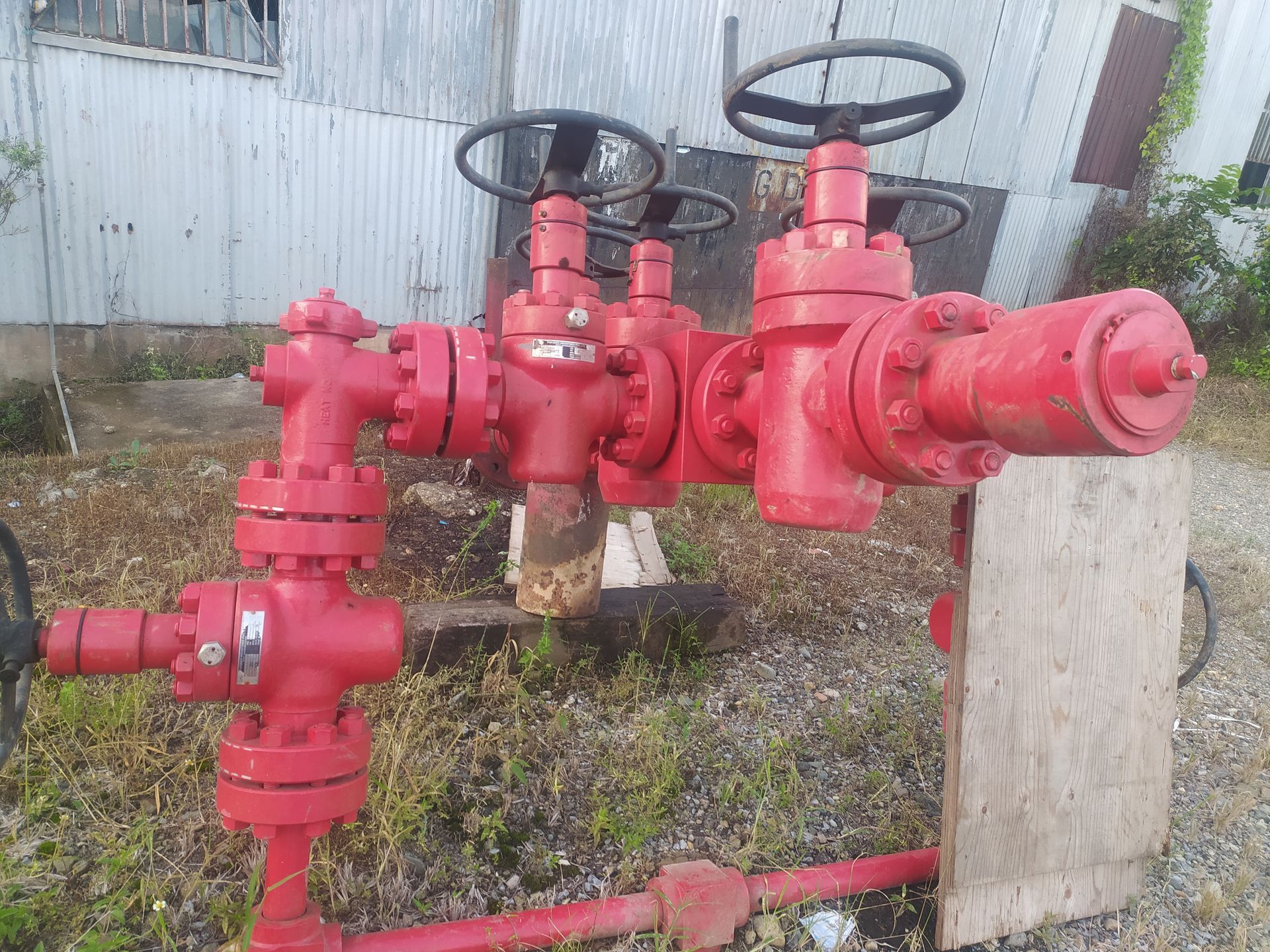 Red industrial valves and pipes in an outdoor setting.