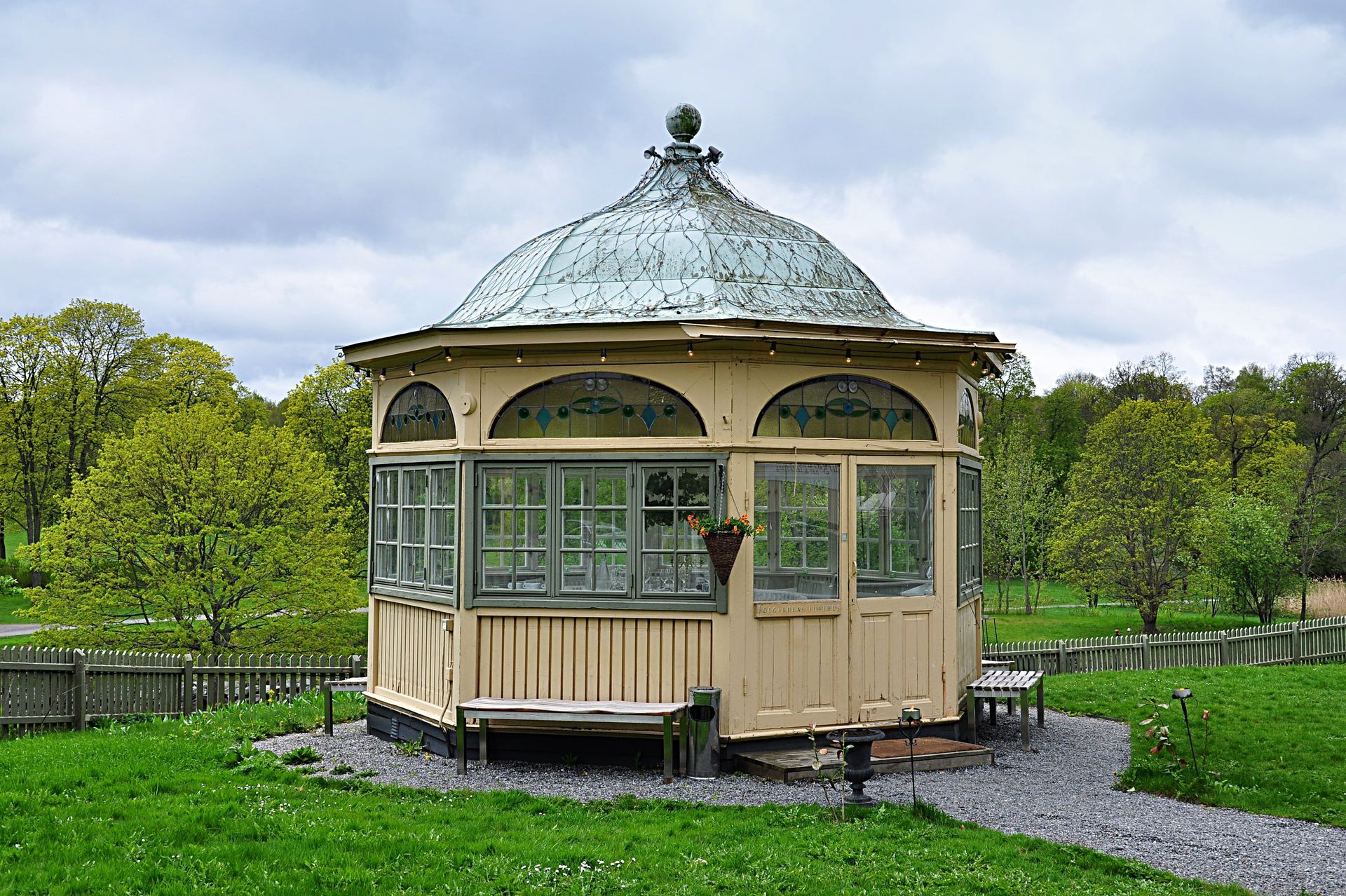 A glass-enclosed gazebo, which is perfect for a greenhouse in a residential backyard