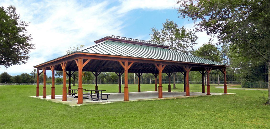 A white backyard pergola at a residential home with outdoor furniture and blooming greenery 
