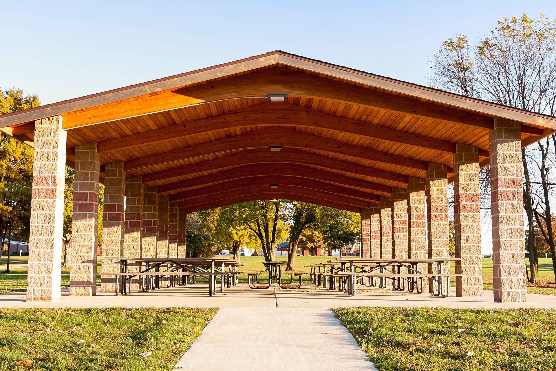 A custom-built pavilion in a public picnic space, with the sun shining and blue skies at SummerHouse Outdoor Structures near Central Pennsylvania