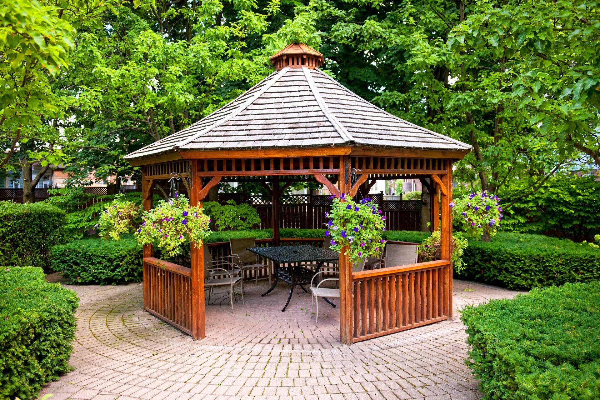 A backyard gazebo with outdoor chairs and tables, and without any screens around the structure