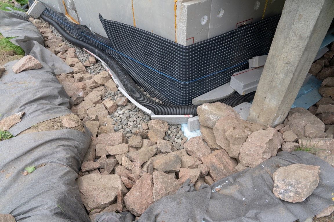 Foundation waterproofing with drainage membrane and gravel.