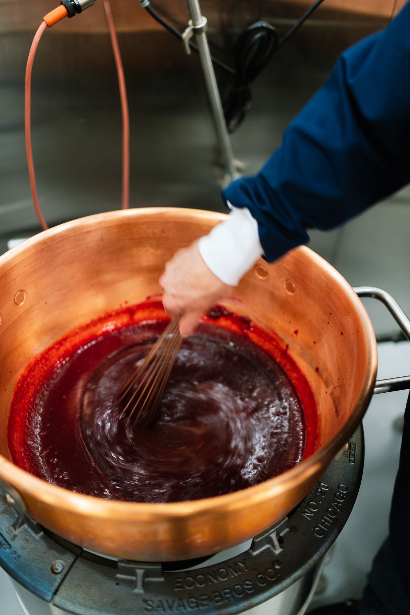 Stirring fruit puree in a copper pot with a whisk