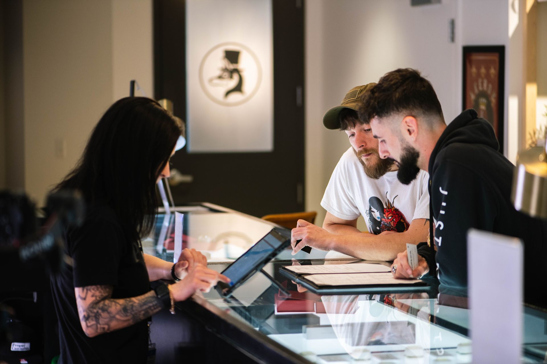 A group of people are sitting at a counter at a Proper Dispensary looking at a menu.