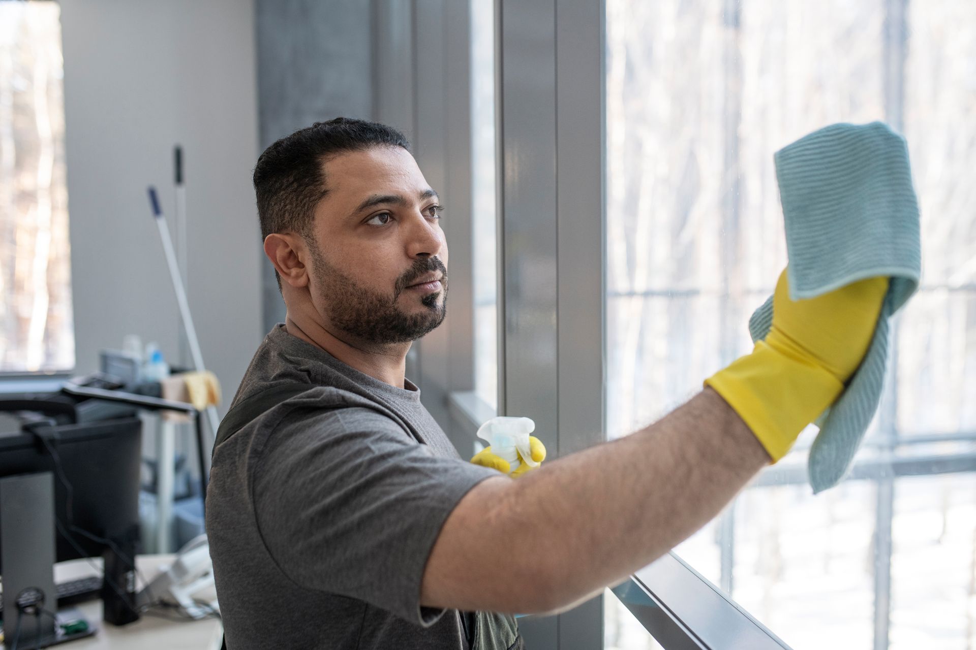 A man is cleaning a window with a cloth in an office.