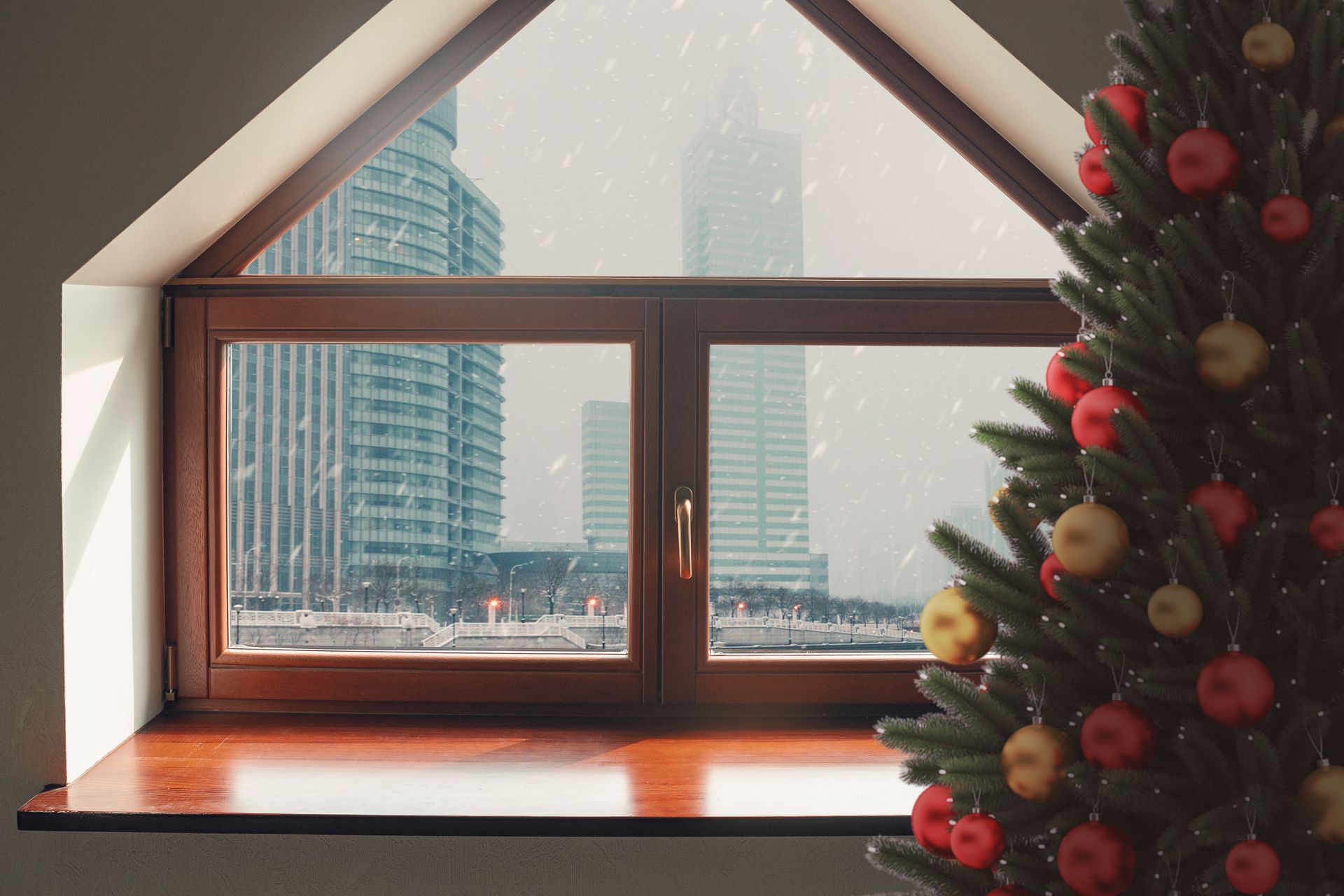 Christmas tree next to a window with a snowy city view.