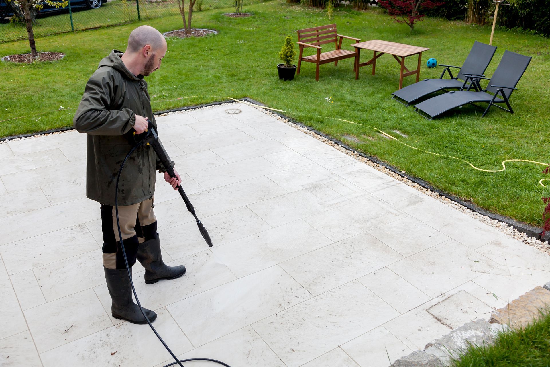A man is cleaning a patio with a high pressure washer.