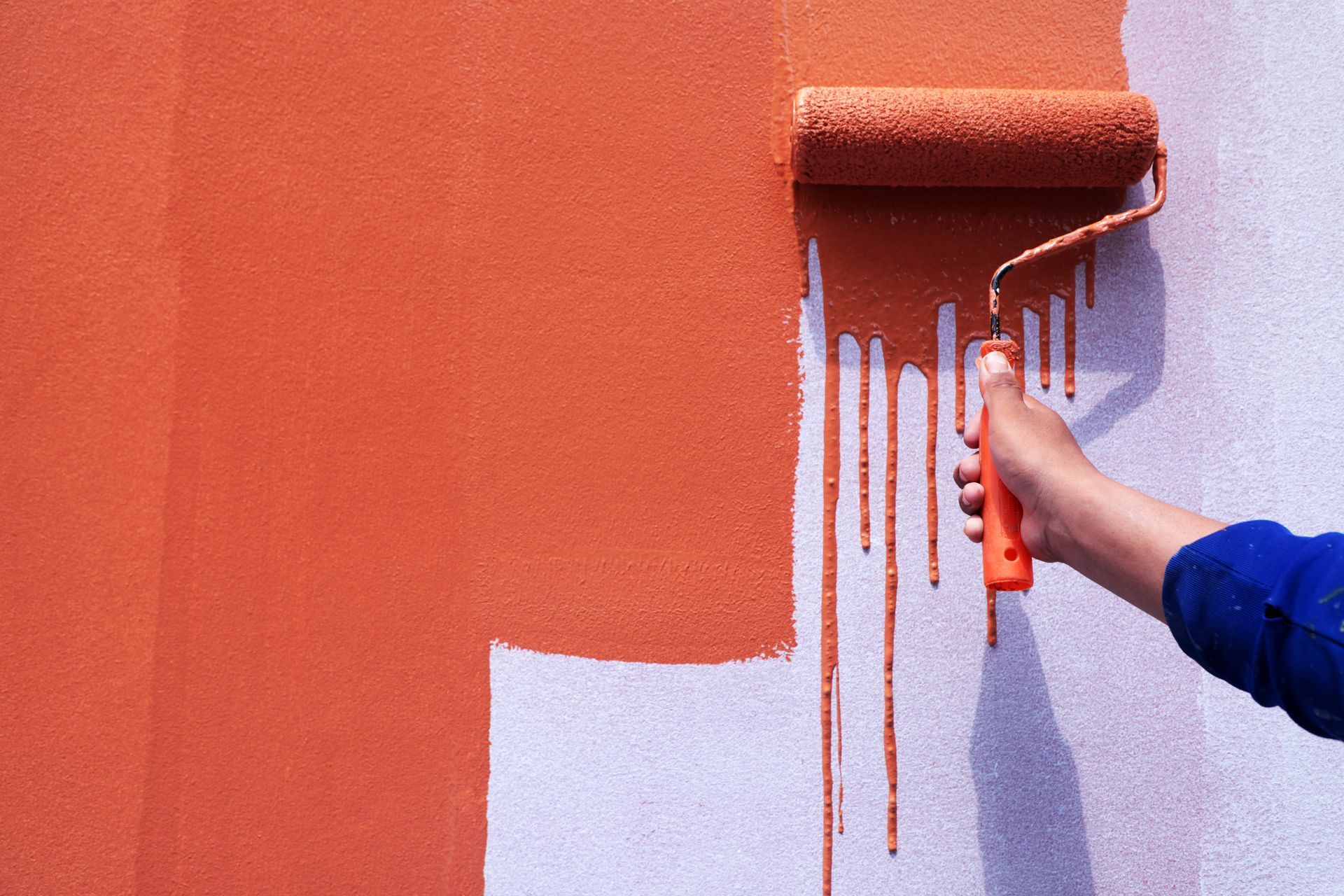 A person is painting a wall with a paint roller.