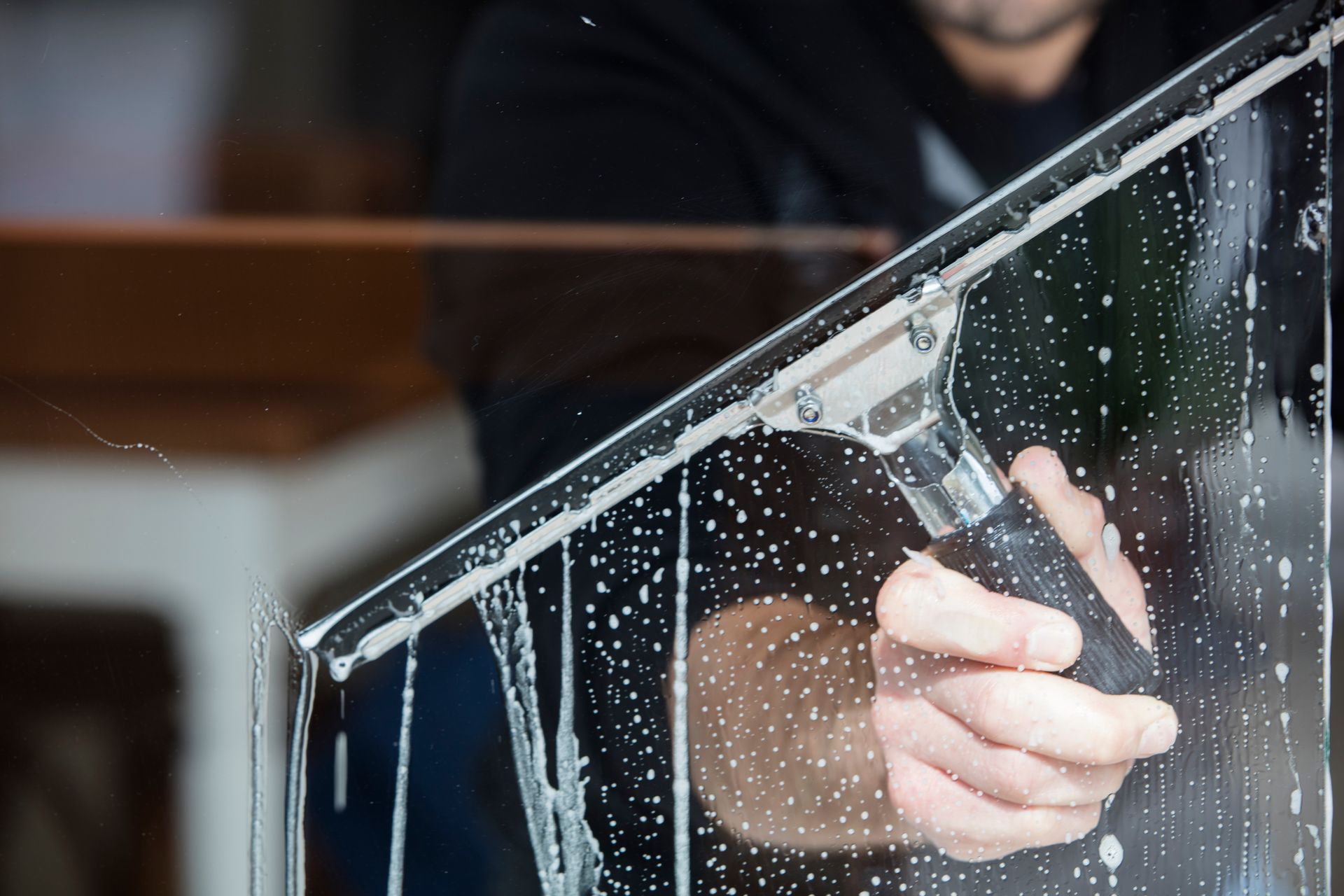 A man wearing yellow gloves is cleaning a window with a cloth.