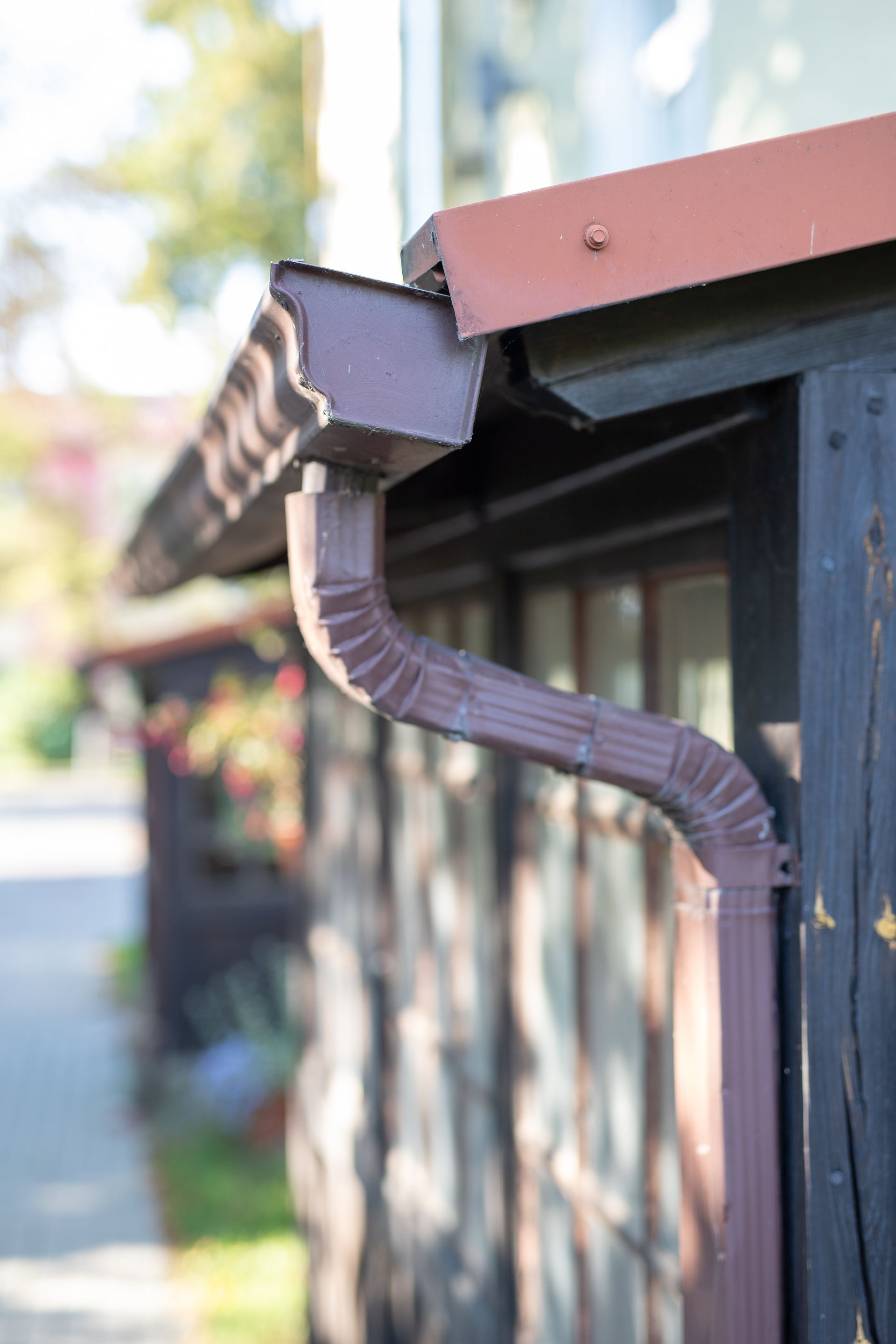 A close up of a brown gutter on the side of a building.