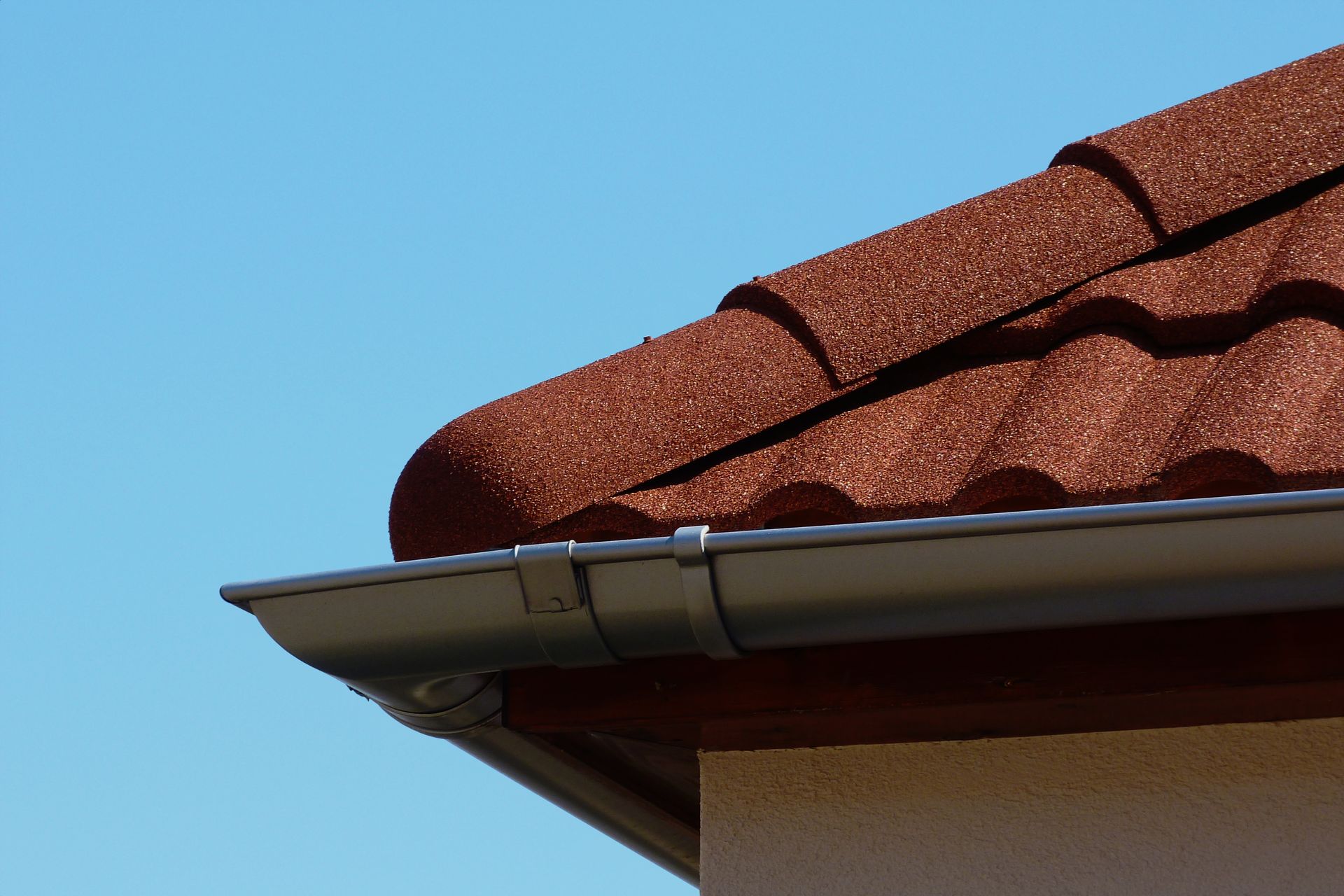 A close up of a gutter on a roof with a blue sky in the background