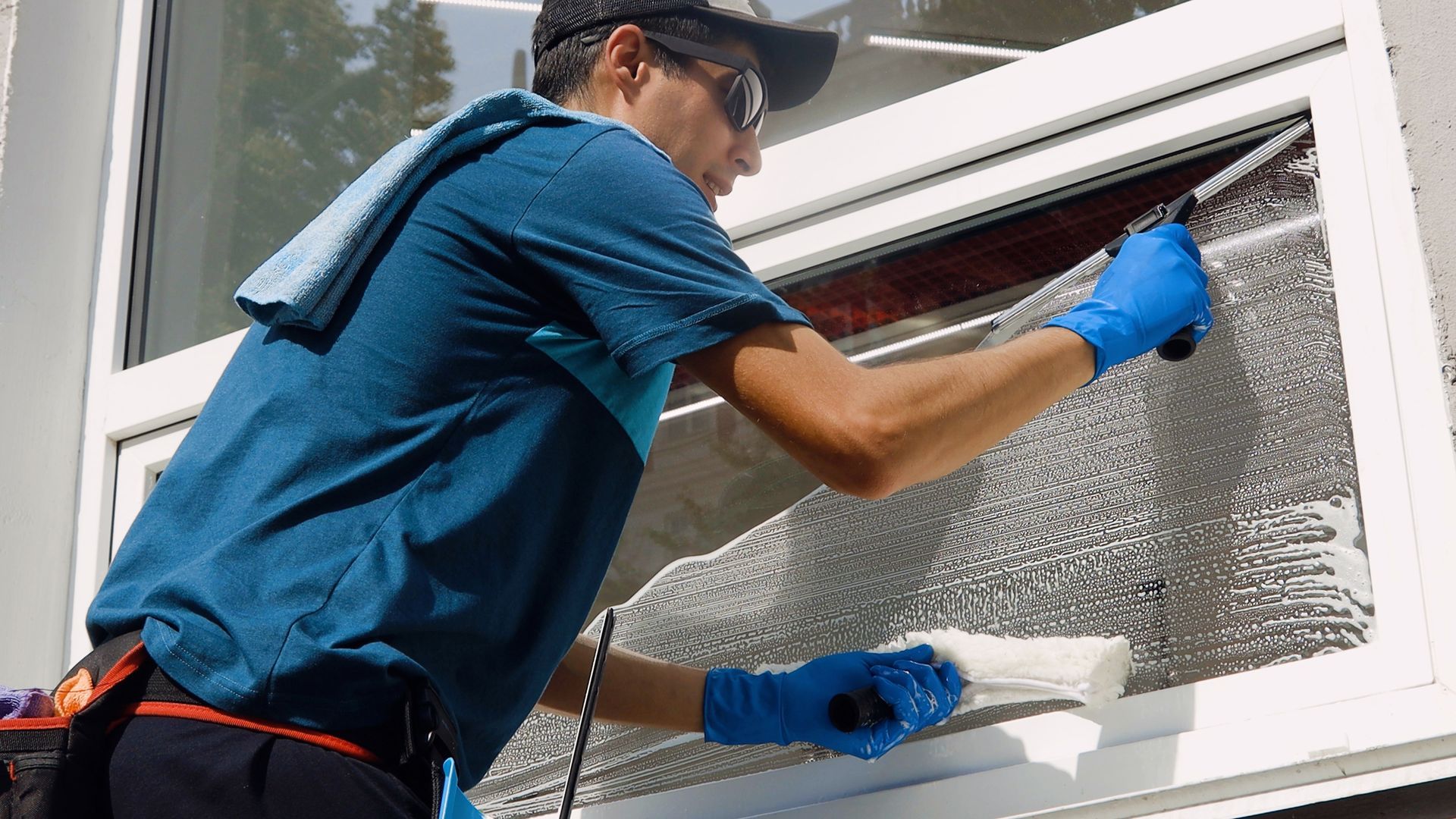 A man is cleaning the windows of a large house.