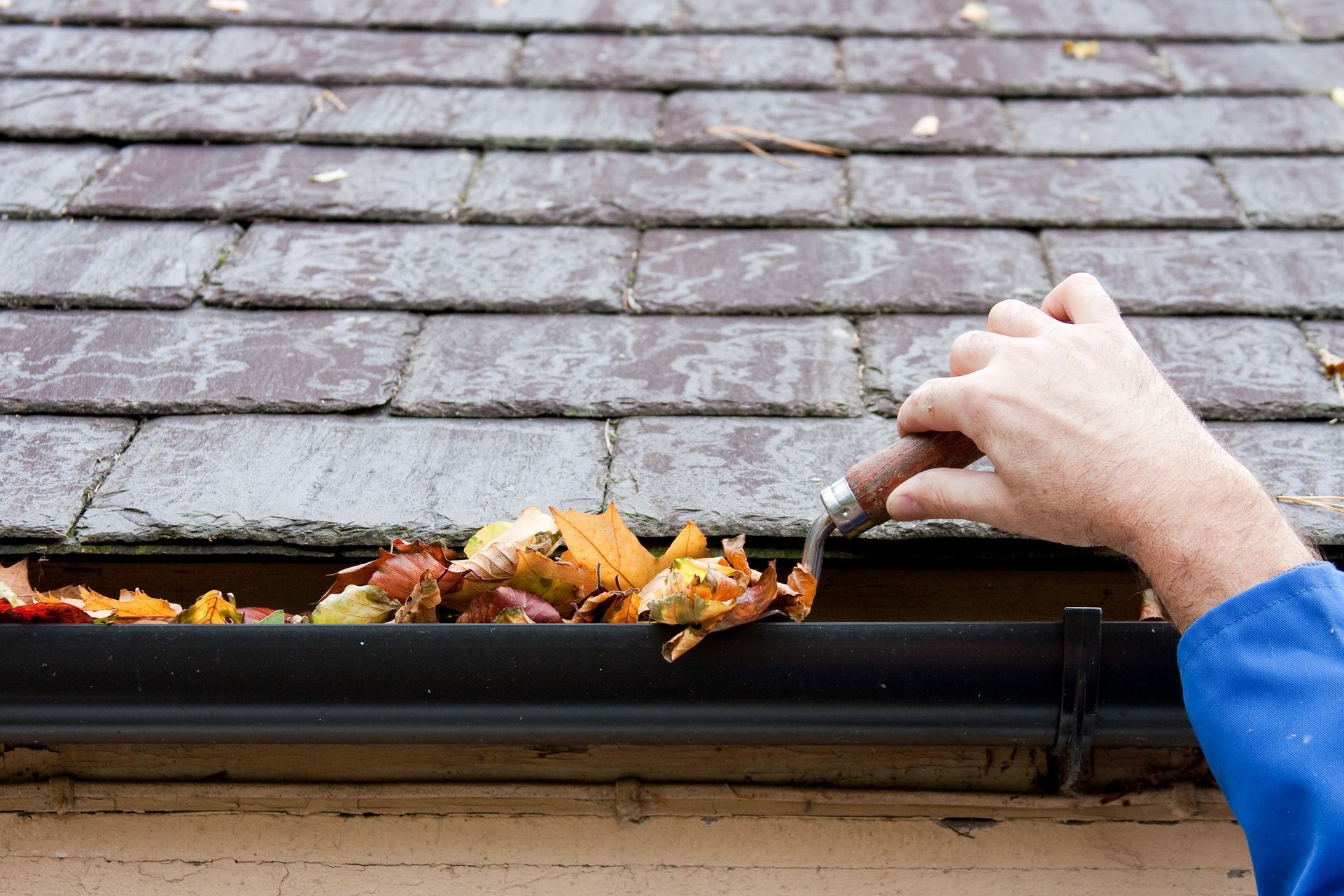 A person is cleaning a gutter with a fork.