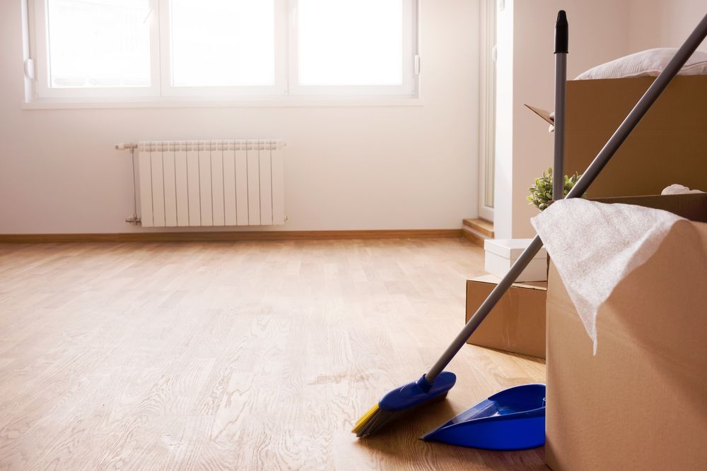 An empty room with boxes and a broom and dustpan on the floor.