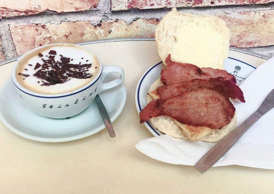 A bacon toastie next to a cup of coffee